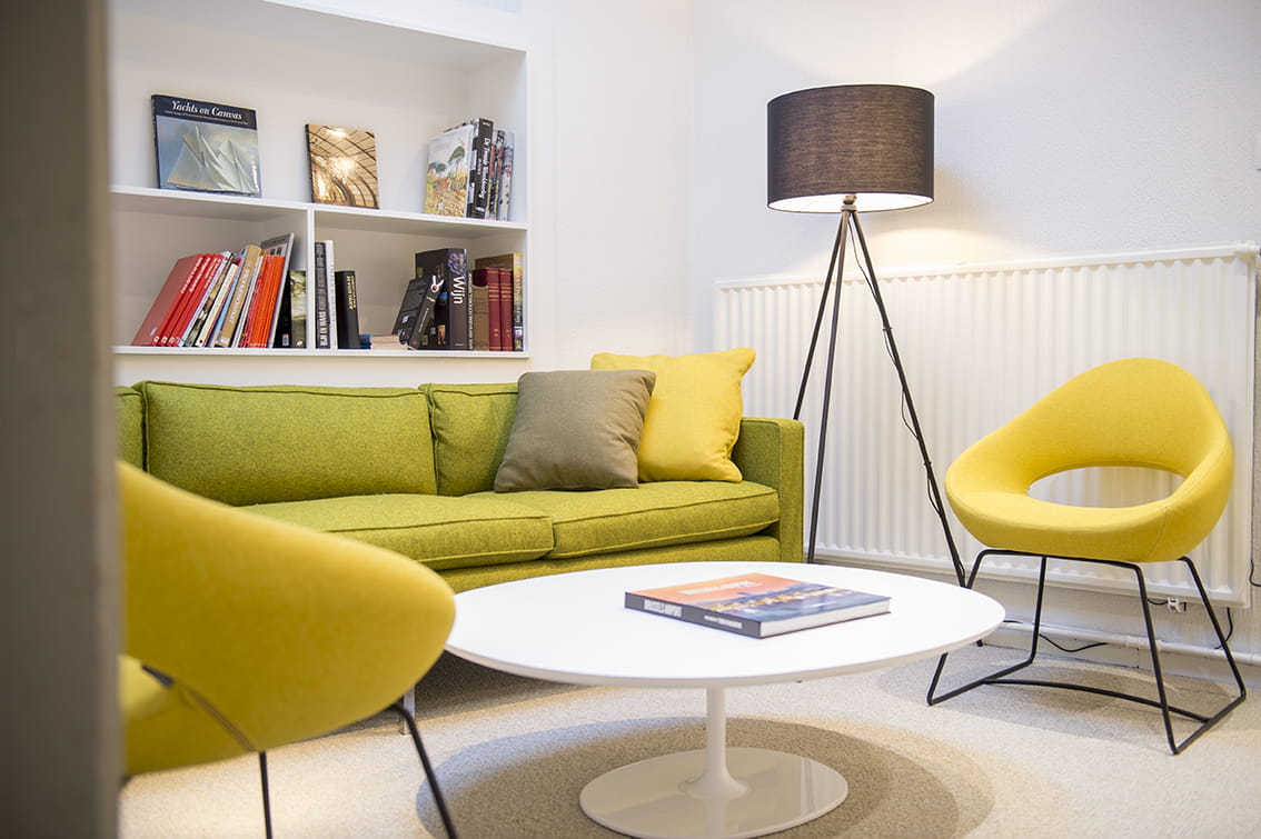 Ontvangstruimte met gele kuipzetel en lichtgroene zetel